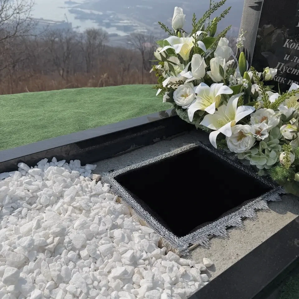 Место для захоронения урны со светлой отсыпкой и белой цветочной композицией