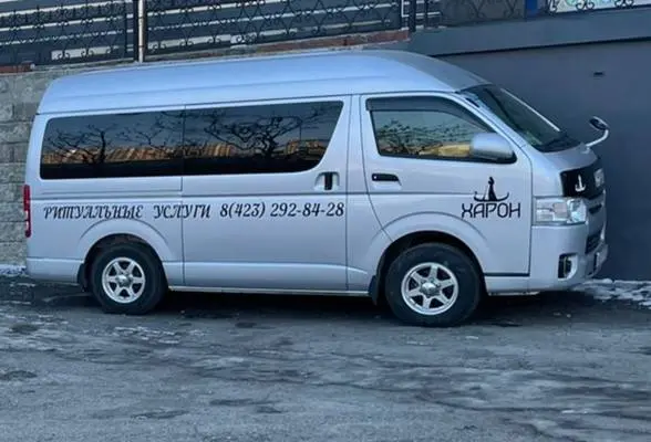 Серебристый микроавтобус Hiace с символикой «Харона»